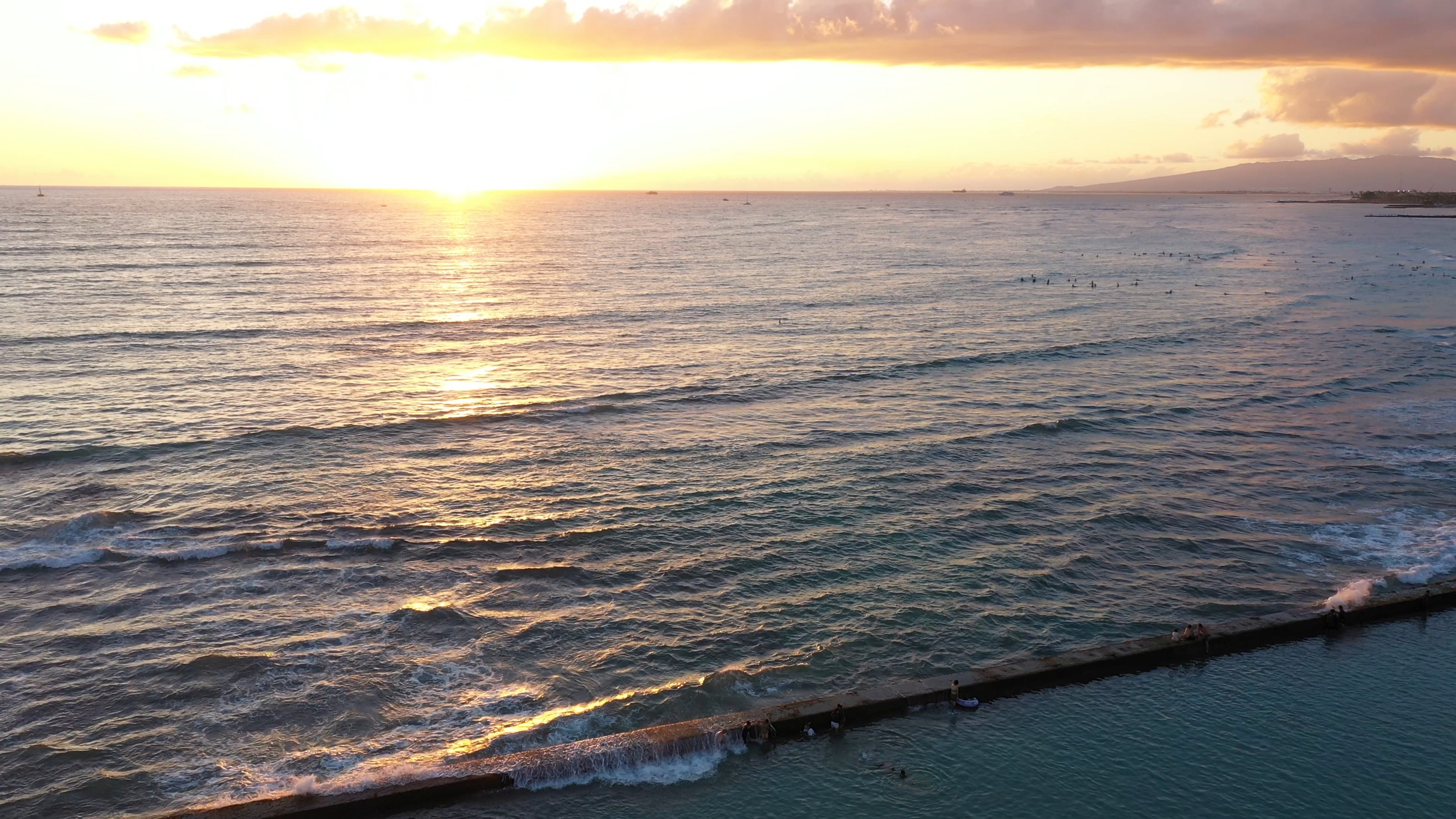 Sunset at waikiki beach with golden hour pau hana happy hour views.
